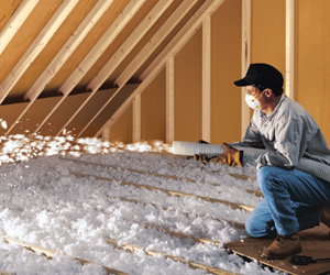 Worker installing insulation in an attic.