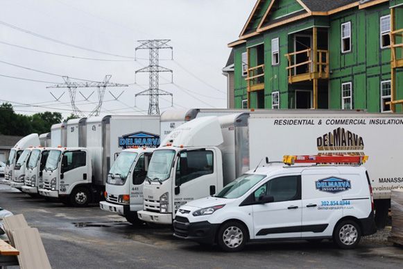 Delmarva Insulation trucks parked in front of an apartment complex under construction.