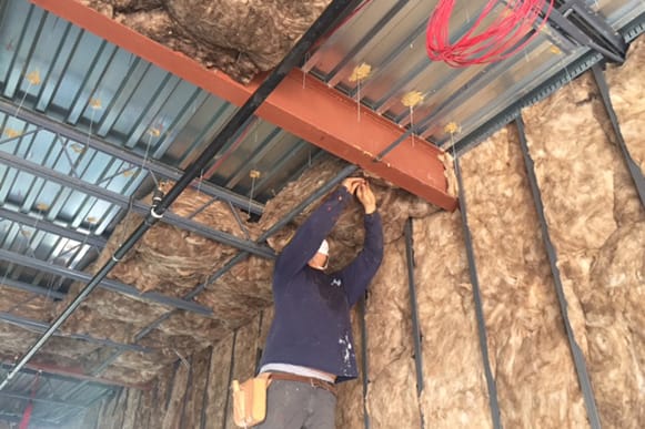 Worker installing insulation in a retail space.