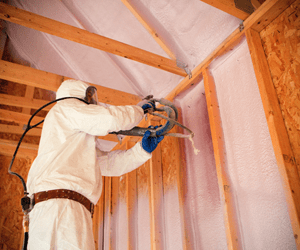 Worker installing spray foam insulation.