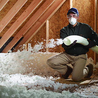 Worker installing blown-in insulation in an attic.
