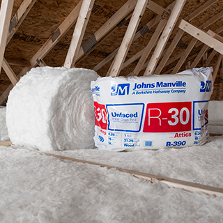 White rolls of insulation on an attic floor.