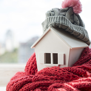 Small white home model with a grey scarf and red hat.