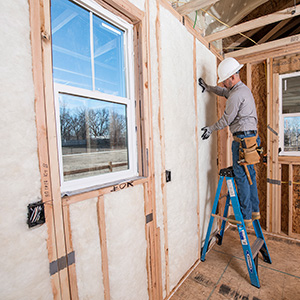 Man installing fiberglass wall insulation.