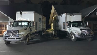 Two Delmarva Insulation trucks parked outside of a business in the evening.