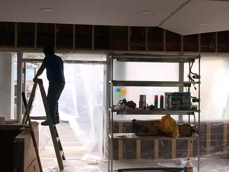 Worker installing spray foam in the wall of a Dominos Pizza restaurant.