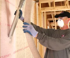 Worker installing blown in wall insulation