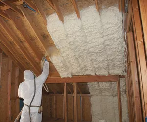 Worker installing spray foam in a ceiling.