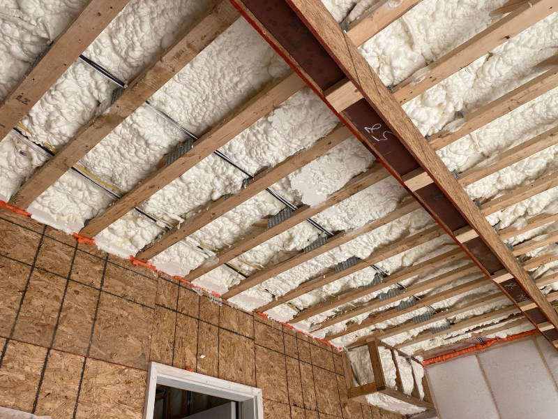 Open cell spray foam applied in a garage ceiling to keep second floor rooms warm.