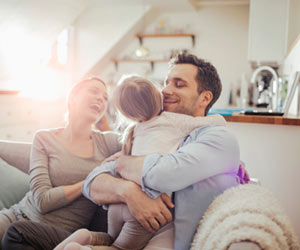 Happy family hugging on couch, in Delaware home.