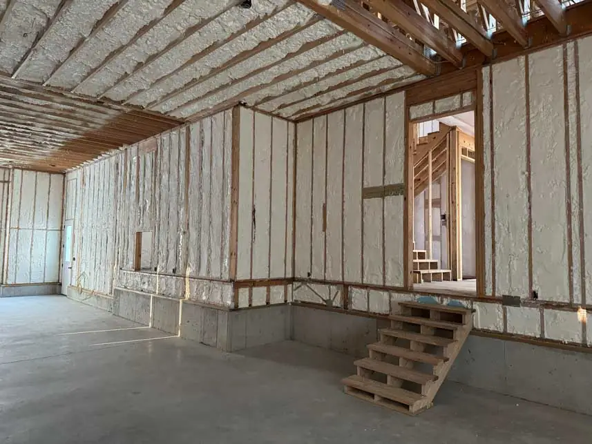 Worker spraying insulation foam onto wall frame