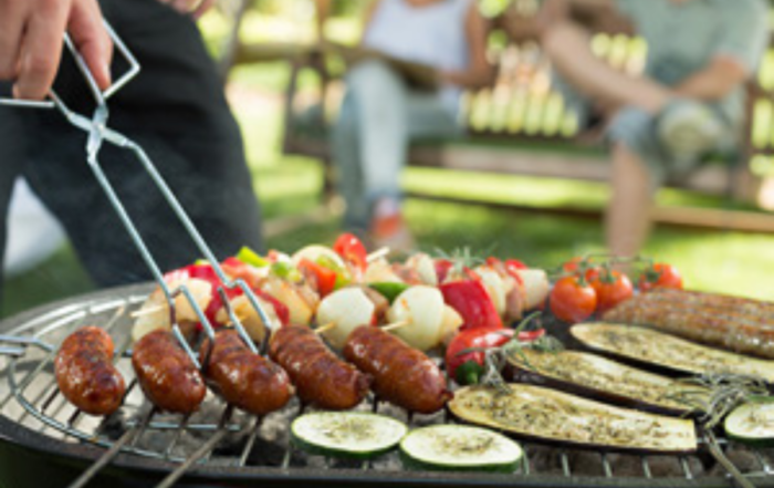 Outdoor gathering with people enjoying grilled skewers