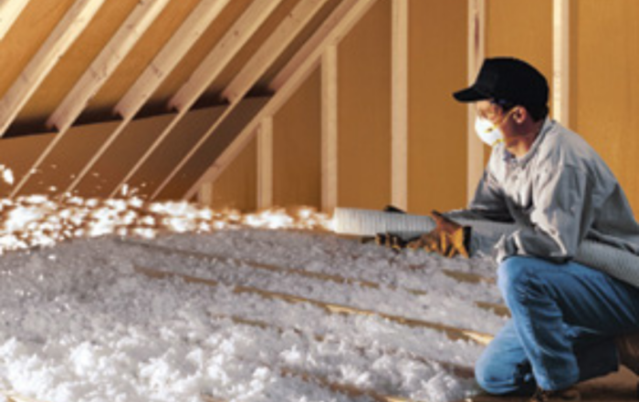 Worker installing blown-in insulation in attic