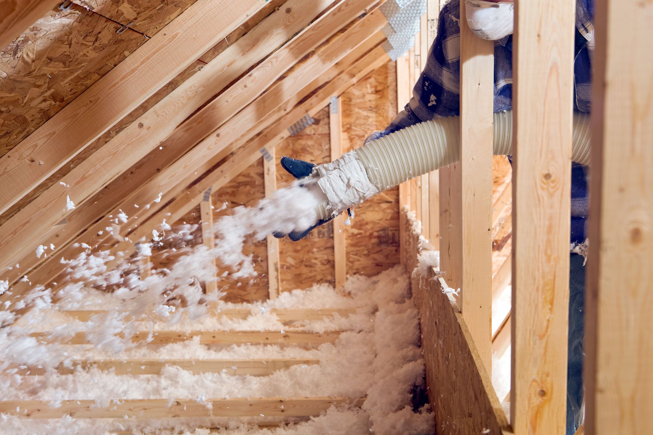 Installer insulating home's attic with blown-in insulation.