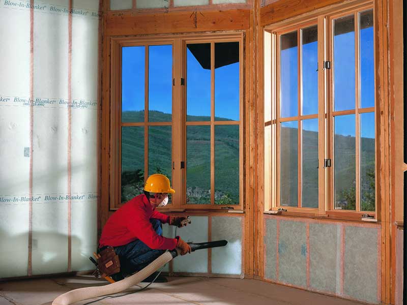 Installer insulating home's walls with a blown-in wall insulation system