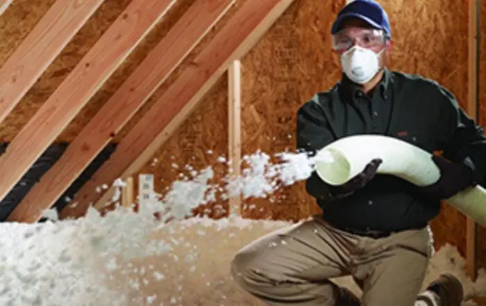 Worker holding insulation sprayer in attic