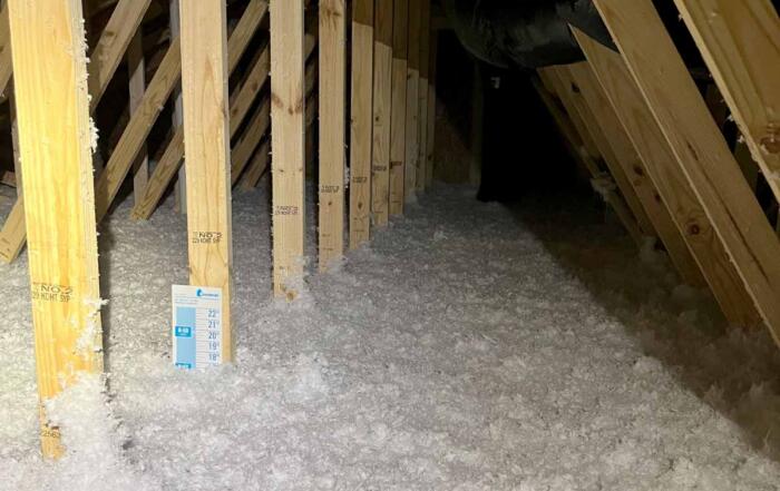 Delmarva Insulation blown-in fiberglass insulation covering an attic floor between roof trusses.